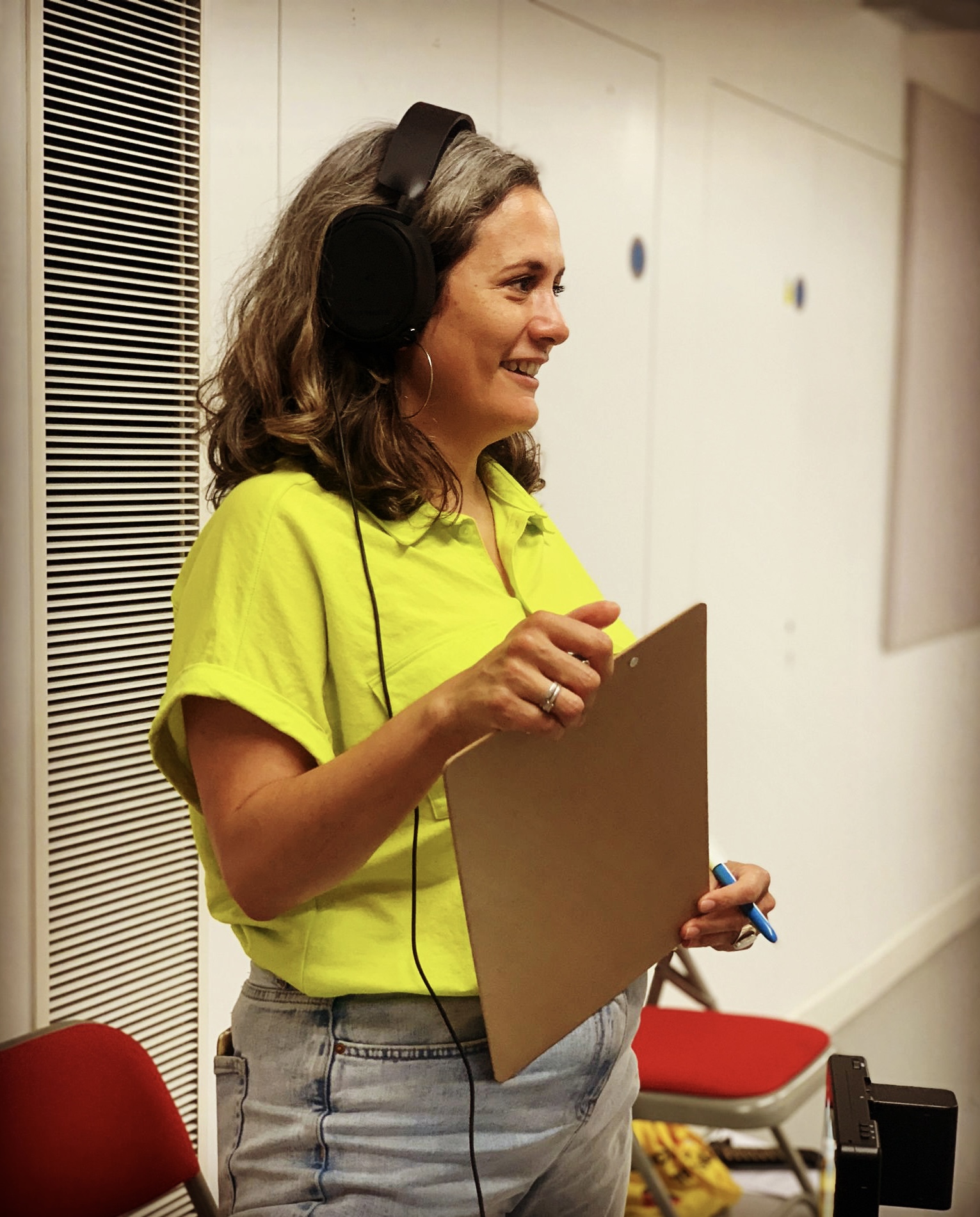 Emma Hill directing for British Youth Opera, wearing headphones and carrying a clipboard