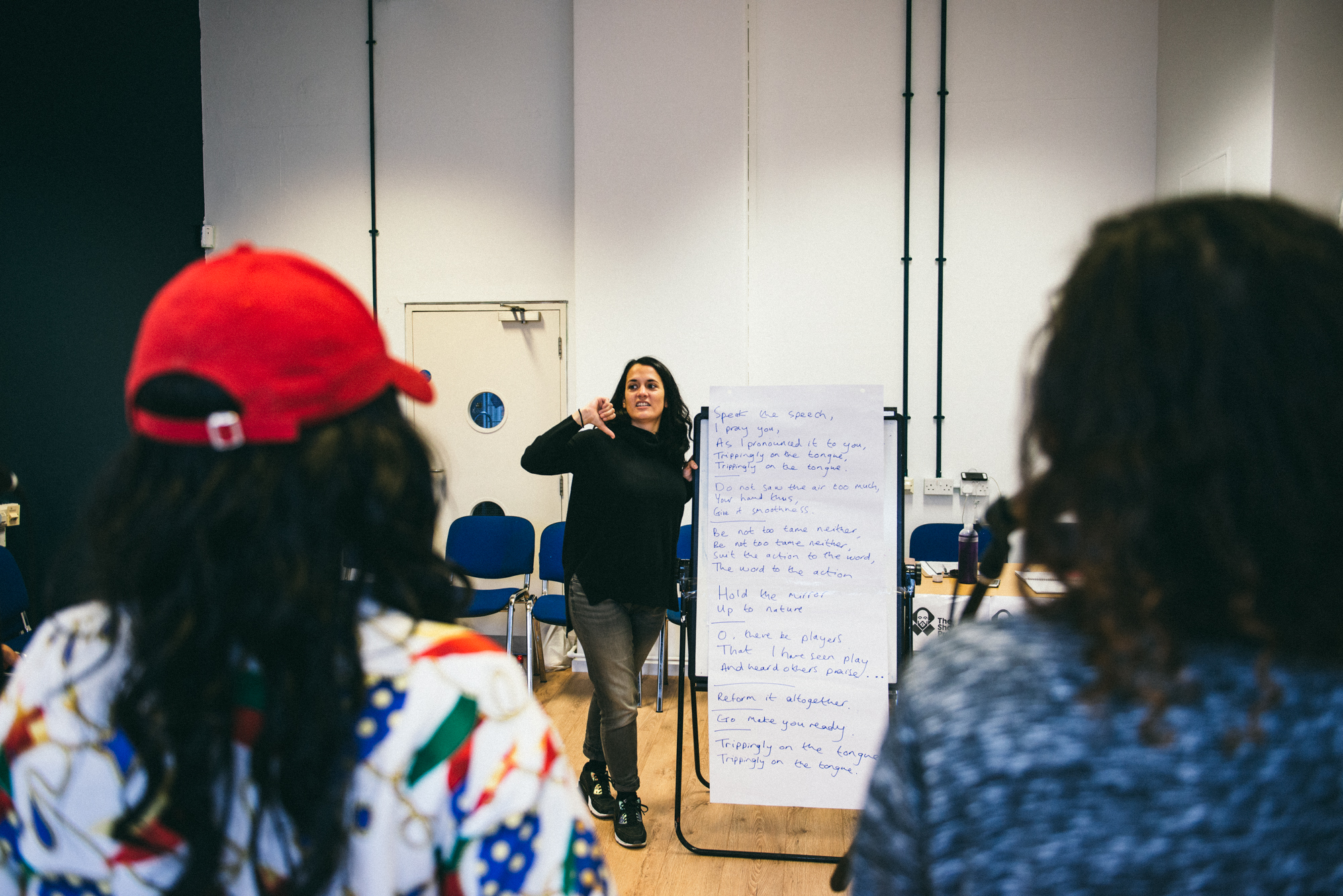 Emma Hill directing The Shakespeare Project, standing in front of a flipchart with Shakespearean text written on it