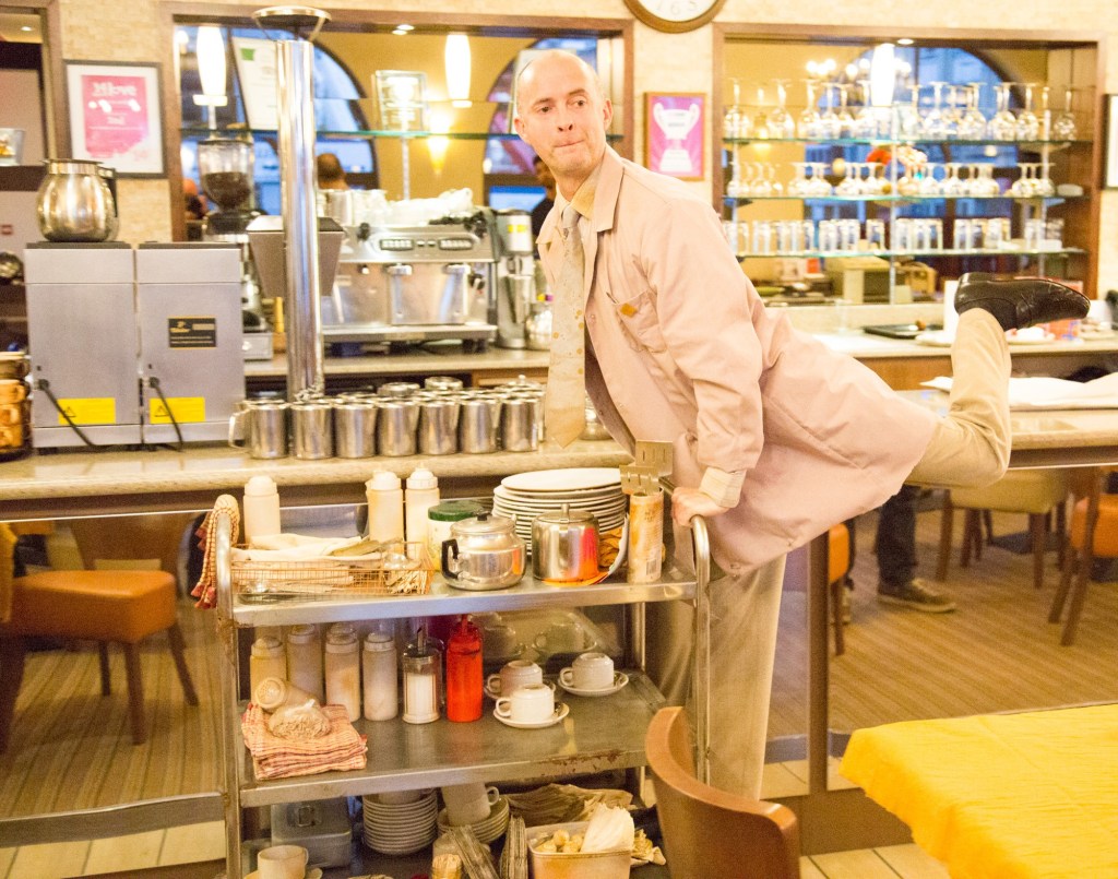 Darren Southworth as Gram in Chip Shop - The Musical, gliding on a buffet trolley